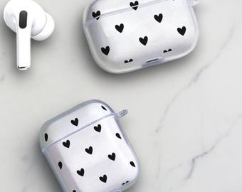 Peut inclure: Deux étuis transparents pour AirPod avec un motif de cœurs noirs. Les étuis sont sur une surface en marbre blanc.