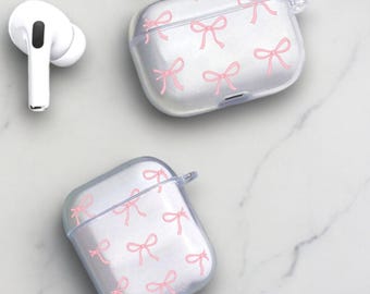 May include: Two clear plastic cases for AirPods with a pink bow pattern. The cases are on a white marble surface.
