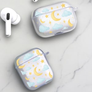 Peut inclure: Étui transparent en plastique pour écouteurs sans fil avec un motif de lune et d'étoiles. L'étui a un fond bleu clair avec des lunes et des étoiles dorées.