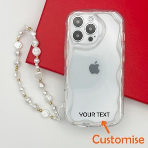 Op de afbeelding: Een transparante telefoonhoes met een golvend ontwerp en een aanpasbaar tekstgebied met de tekst "YOUR TEXT". De hoes wordt geleverd met een witte parel- en gouden ketting.