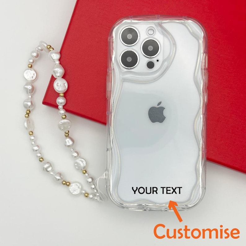 Op de afbeelding: Een transparante telefoonhoes met een golvend ontwerp en een aanpasbaar tekstgebied met de tekst "YOUR TEXT". De hoes wordt geleverd met een witte parel- en gouden ketting.
