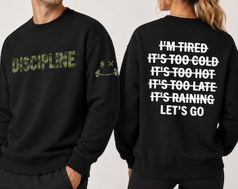 May include: Black sweatshirts. One has the word "DISCIPLINE" in camouflage print on the front and a small smiley face on the sleeve. The other has white text on the back: "I'M TIRED IT'S TOO COLD IT'S TOO HOT IT'S TOO LATE IT'S RAINING LET'S GO."