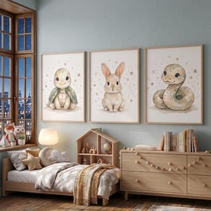 May include: Three framed nursery art prints depicting a turtle, a rabbit, and a snake, all in a soft watercolour style. The prints are in a light-toned room with a wooden bed, chest of drawers, and a window with a city view.