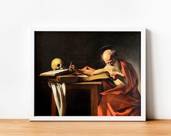 May include: Framed artwork showing an elderly man in a red robe writing at a wooden table. A skull and open book are on the table. The painting has a dark background and is in a white frame.