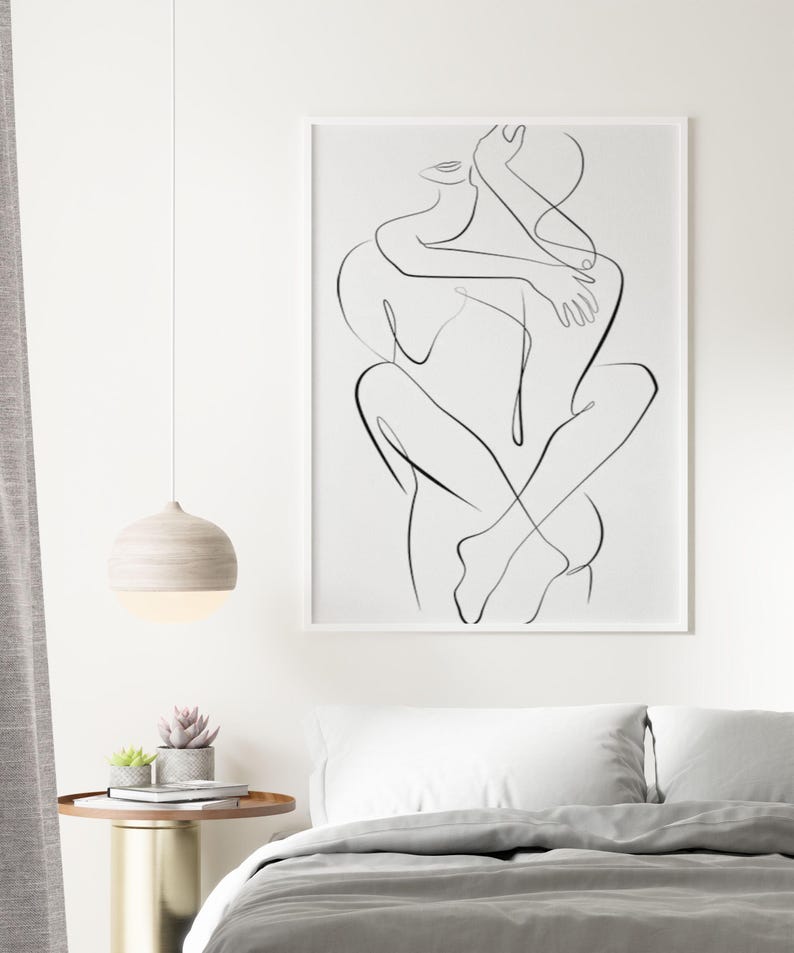 Pu&ograve; includere: Una stampa artistica in bianco e nero incorniciata raffigurante due figure che si abbracciano. L'opera d'arte &egrave; esposta sopra un letto con biancheria da letto bianca e un piumino grigio. Una lampada a sospensione rotonda in legno pende dal soffitto e un piccolo tavolino con piante &egrave; nelle vicinanze.
