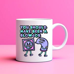 May include: White ceramic mug with the text "YOU SHOULD HAVE BEEN A BLOWJOB" in teal and purple. The mug features cartoon illustrations of a condom and a sperm cell with legs, set against a pink background.