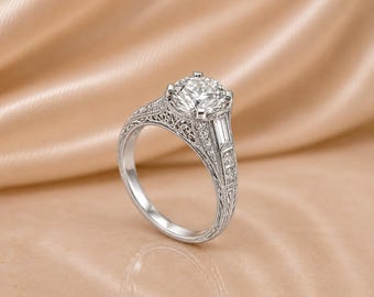 May include: A silver-coloured ring featuring a large round-cut centre stone, flanked by baguette-cut side stones and smaller round accent stones. The band displays intricate filigree metalwork along the sides, showcasing a detailed, textured pattern.