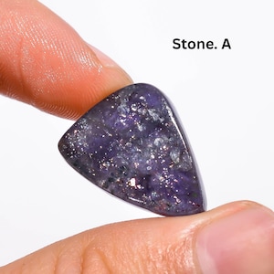 Könnte beinhalten: Ein dreieckiger violetter Edelstein mit einer texturierten, kristallinen Oberfläche, die durchgehend schillernde, metallisch wirkende Flecken aufweist. Der Stein ist in der oberen rechten Ecke mit dem Text Stone. A auf weißem Grund versehen.