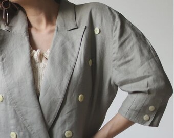 Pode incluir: Um blazer verde claro de abotoamento duplo com botões grandes, redondos e amarelo claro. O blazer tem lapelas entalhadas e um ajuste descontraído. As mangas são de três quartos. O blazer tem dois bolsos frontais.