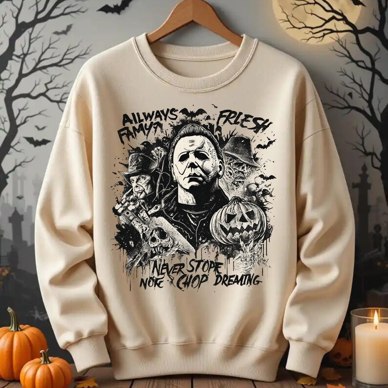 May include: Beige crewneck sweatshirt featuring a black and white graphic of a horror movie character, a jack-o'-lantern, and the text "AILWAYS FAMYA FRLSH" and "NEVER STOPE NORE CHOP DREMIN". The design has a Halloween theme.