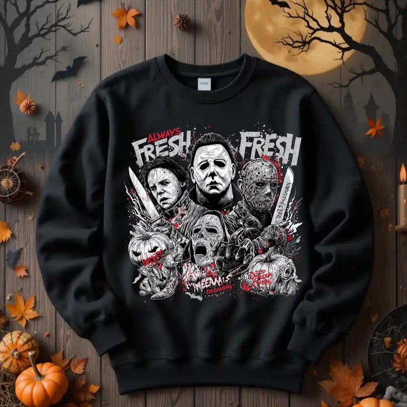 May include: Black sweatshirt featuring a graphic design with the text "ALWAYS FRESH FRESH" and images of horror movie characters. The design includes pumpkins, knives, and the words "WEENIES DREAMING".
