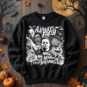 May include: Black sweatshirt with a white graphic featuring horror movie characters and the text "ALWAYS FRESH" and "NEAM STOP DREAMING". The design includes images of Michael Myers, Freddy Krueger, and Jason Voorhees, perfect for Halloween.