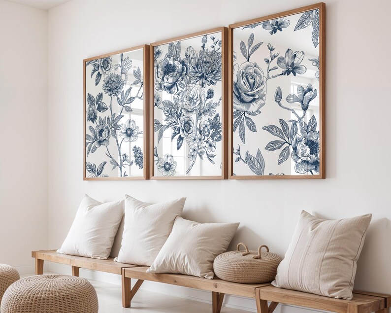 Pu&ograve; includere: Tre opere d'arte incorniciate con un design floreale blu. L'opera d'arte &egrave; esposta sopra una panca di legno con cuscini bianchi e un cestino intrecciato. Il motivo floreale presenta dettagliate illustrazioni botaniche in tonalit&agrave; di blu su sfondo bianco.