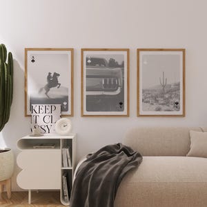 Op de afbeelding: Drie ingelijste zwart-wit prints met schoppen aas symbolen. E&eacute;n toont een paard en ruiter, een andere een auto en de derde een woestijnlandschap met een cactus. De frames zijn lichtbruin.