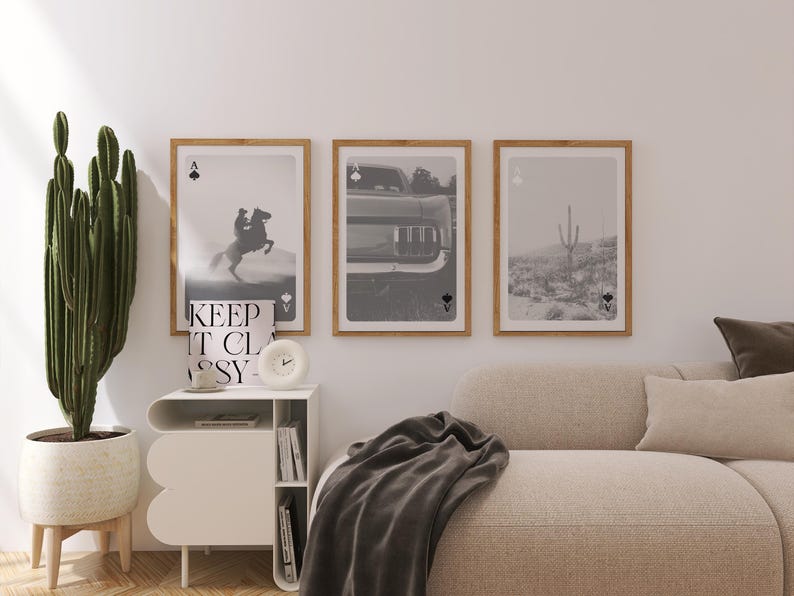 Op de afbeelding: Drie ingelijste zwart-wit prints met schoppen aas symbolen. E&eacute;n toont een paard en ruiter, een andere een auto en de derde een woestijnlandschap met een cactus. De frames zijn lichtbruin.