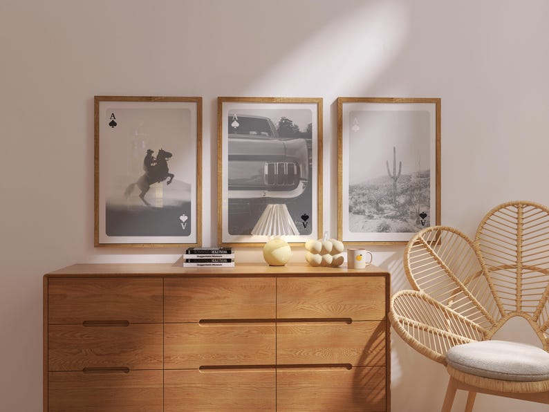 Op de afbeelding: Drie ingelijste kunstprints met een speelkaartthema. De prints tonen een paard en ruiter, een klassieke auto en een woestijnlandschap. De frames zijn lichtbruin en de kunst is in zwart-wit.