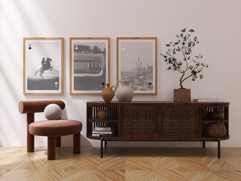 Op de afbeelding: Een stijlvolle woonkamersc&egrave;ne met ingelijste zwart-wit kunstprints, een bruine houten kast en een unieke stoel. De kunst omvat een paard, een auto en een woestijnlandschap. Decoratieve vazen en een potplant dragen bij aan de esthetiek.