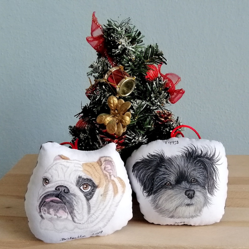Puede incluir: Dos adornos navide&ntilde;os personalizados con retratos pintados a mano de perros. El adorno de la izquierda presenta un bulldog blanco y marr&oacute;n con el nombre "Bristol" y el a&ntilde;o "2019". El adorno de la derecha presenta un perro blanco y negro con el nombre "Toppy" y el a&ntilde;o "2019".