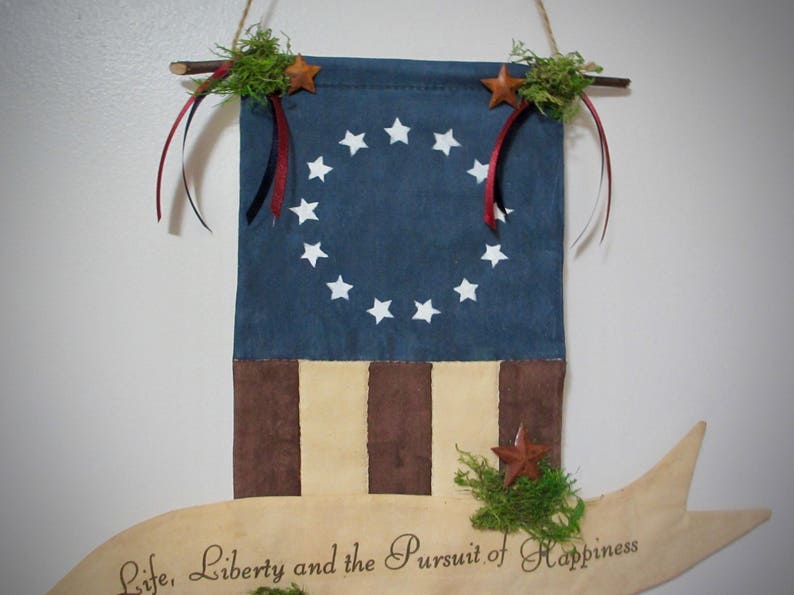 May include: A blue and brown fabric wall hanging with a circle of white stars and the text "Life, Liberty and the Pursuit of Happiness".