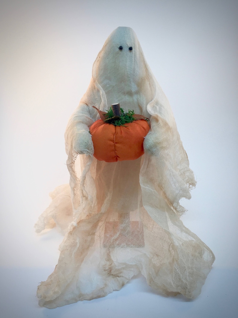 Free standing halloween ghost with pumpkin and flowing cheesecloth overlay.   Ghost holds a fabric pumpkin