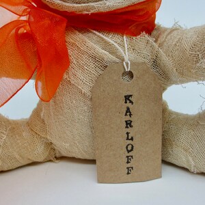 May include: A handmade burlap mummy doll with an orange ribbon and a brown tag that says "KARLOFF".