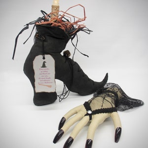 May include: A black witch's boot with a lit candle on top, surrounded by straw. A black lace glove with long, dark nails is on the right side of the image. The boot has a tag that reads: "When witches go riding, and black cats are seen, the moon laughs and whispers, 'Tis near Halloween.'"