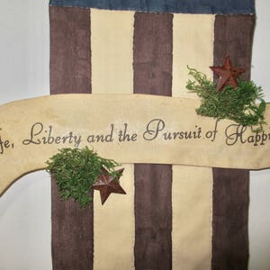 May include: A decorative banner with a brown, white, and blue striped background. The banner has a white ribbon with the text "Life, Liberty and the Pursuit of Happiness" written in black. The ribbon is curved and has a brown star at the end.
