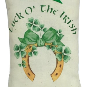 An off white mini pillow. printed on muslin.  The pillow has a green shamrock and horseshoe design with the text 'Luck O' the Irish' in green lettering and a small green bow at the top    sized at 4" x 6"