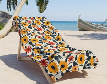 Könnte beinhalten: Ein Strandstuhl mit einem floralen Kissen. Das Kissen hat einen weißen Hintergrund mit orangefarbenen und gelben Sonnenblumen und dunkelgrünen Blättern.
