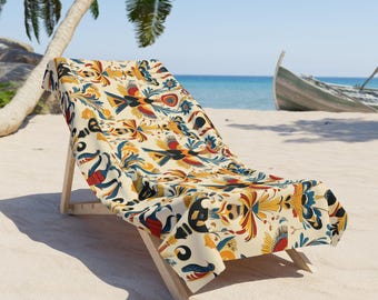 Könnte beinhalten: Ein Strandstuhl mit einem farbenfrohen gemusterten Stoff, der ein sich wiederholendes Muster aus stilisierten Vögeln, Blumen und geometrischen Formen zeigt. Der Stuhl ist aus Naturholz gefertigt und hat eine hellbraune Oberfläche. Der Stuhl steht auf einem Sandstrand mit einer Palme im Hintergrund.