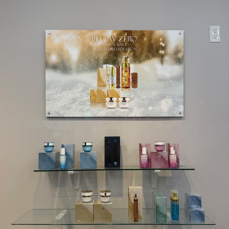 K&ouml;nnte beinhalten: Eine Pr&auml;sentation von Hautpflegeprodukten mit einem schneebedeckten Hintergrund, auf dem der Text "BELOW ZERO - SWISS SCIENCE - SKIN CELL RESTORATION" steht. Die Produkte sind in goldenen und wei&szlig;en Verpackungen und umfassen Cremes, Seren und eine Flasche Gesichtswaschmittel.