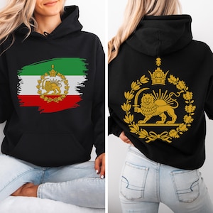 Peut inclure: Sweat à capuche noir avec le drapeau iranien sur le devant et un emblème doré au dos. Le motif avant comprend les couleurs du drapeau : vert, blanc et rouge, avec un emblème doré. Le dos affiche un emblème doré de lion et de soleil.