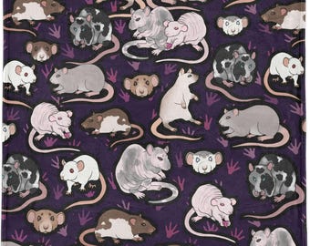 Puede incluir: Una manta morada con un patrón repetido de ratas de dibujos animados en varios colores, incluyendo blanco, gris, marrón y negro. Las ratas se representan en diferentes poses, con largas colas y pequeñas patas. El fondo incluye huellas de patas.
