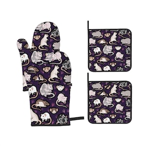 Puede incluir: Un guante de cocina morado y dos agarraderas con un patrón repetido de ilustraciones de ratas variadas en blanco, gris, marrón y negro. Los textiles de cocina están diseñados para cocinar y hornear.