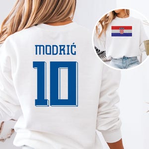 A white sweatshirt with the number 10 and the name "MODRIC" printed on it, along with a small image of the national flag of Croatia.