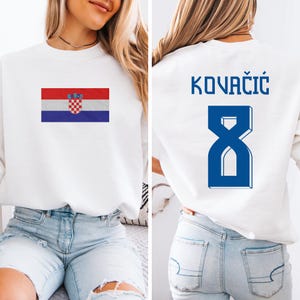 A woman wearing a white sweatshirt with the Croatia national flag and the number 8 on the back.