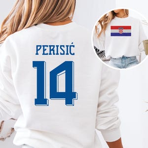 A white sweatshirt with the number 14 and the name "PERISIC" printed on it, along with a small image of the Croatia national flag.