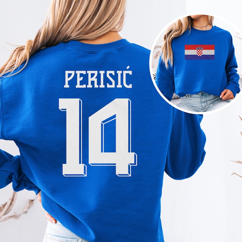 A woman wearing a blue sweatshirt with the number 14 and the word "PERISIC" printed on it.