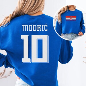A woman wearing a blue sweatshirt with the number 10 and the name "Modric" printed on it.