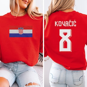 A woman wearing a red shirt with the Croatia national flag and the number 8 on the back, as well as a sports jersey with the name 'KOVACIÓG' and the number '8' on the back.