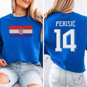 A woman wearing a blue sweatshirt with the Croatia national flag and the number 14 printed on it.