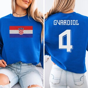 A woman wearing a blue sweatshirt with the Croatia national flag and the number 4 printed on it.