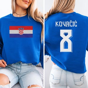 A woman wearing a blue sweatshirt with the Croatia national flag and the number 8 printed on it.