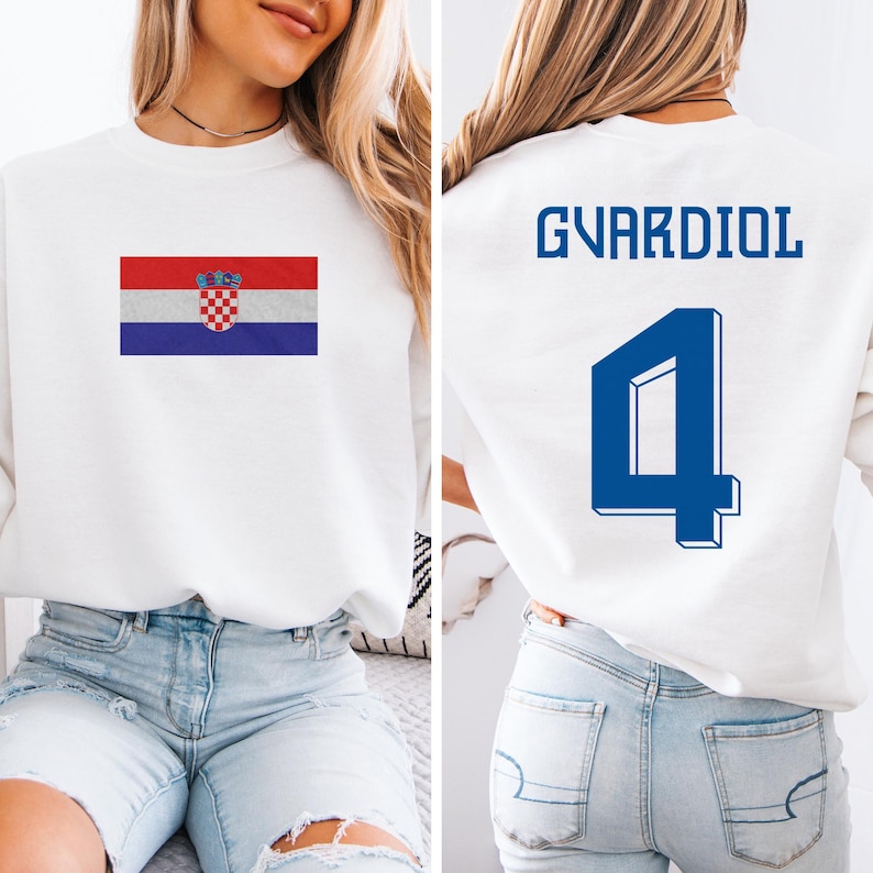 A woman wearing a white sweatshirt with a Croatia flag and the number 4 on the back, as well as a jersey with the name 'GVARDIOL' and the number 4 on the back.