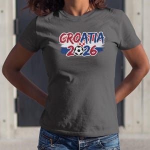 A woman wearing a grey t-shirt with the text "GROATIA 2026" printed on it.