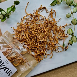 May include: Dried orange-colored mushrooms in a clear plastic bag with a brown paper label that reads "Holy Shitake Mushrooms" and "For Your Good Health".