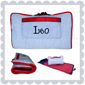 May include: A blue and white striped nap mat with a red border and a pocket. The name "Leo" is embroidered in black. The mat is shown folded and rolled up, and also with a pillow.