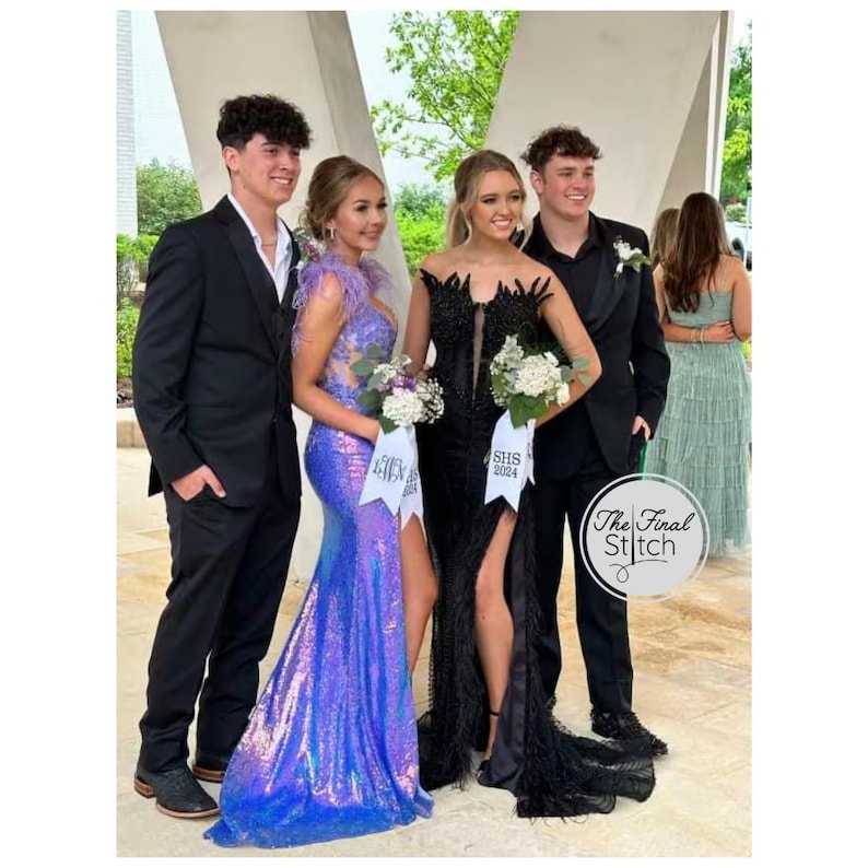 May include: Two individuals in formal attire stand with two others. One wears a floor-length iridescent purple sequined gown with feather accents. The other wears a black floor-length gown with lace detailing and a high slit. Both hold bouquets with ribbons labeled SHS 2024.