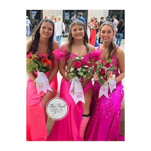 May include: Three individuals wearing floor-length pink gowns, each holding a floral bouquet wrapped in a white ribbon. The ribbons feature the text "Prom 2024" in pink lettering. The gowns vary in shade and texture, including satin and sequined fabrics.