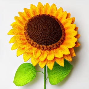 May include: A handmade crochet sunflower featuring vibrant yellow petals, a dark brown centre, and a green stem with leaves. This is a cheerful, decorative item.